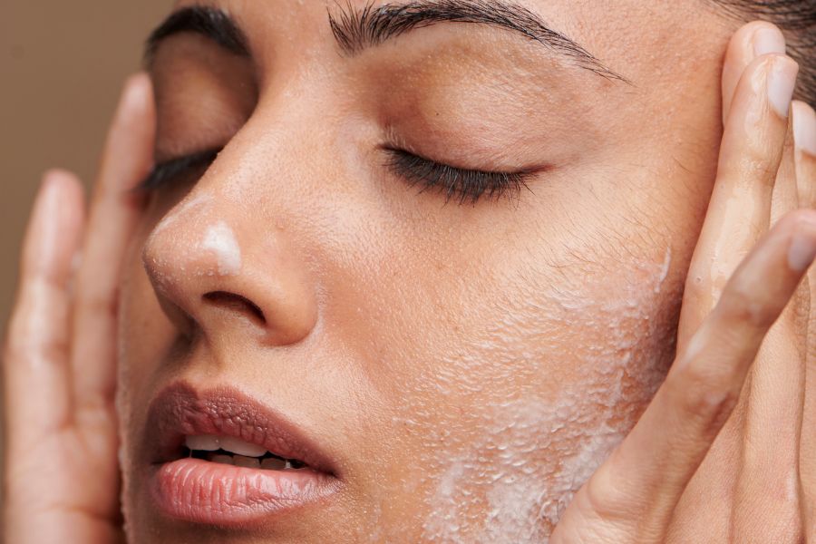 Zoom on a woman's face, we can see her hands on her face, she's using a cleanser