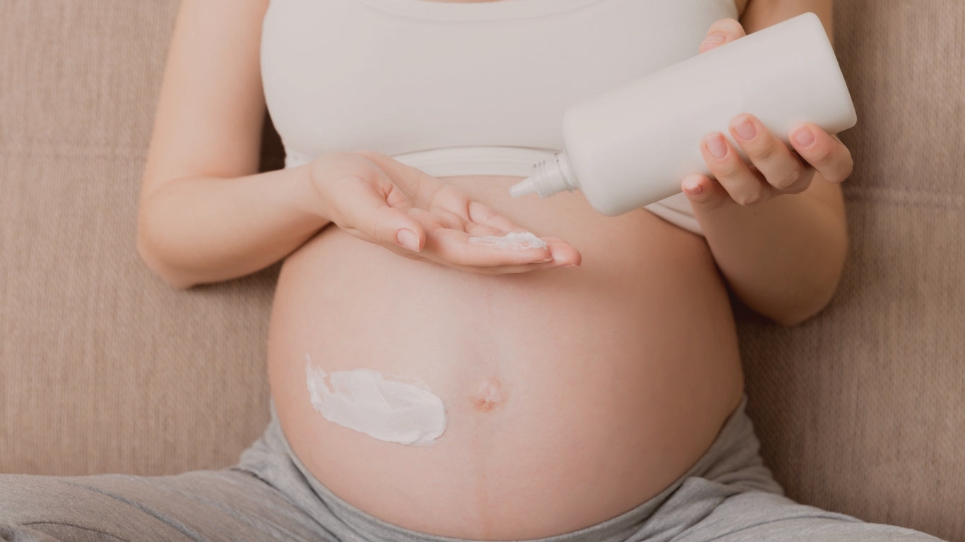 Belly of a pregnant woman, she's applying a clean body lotion