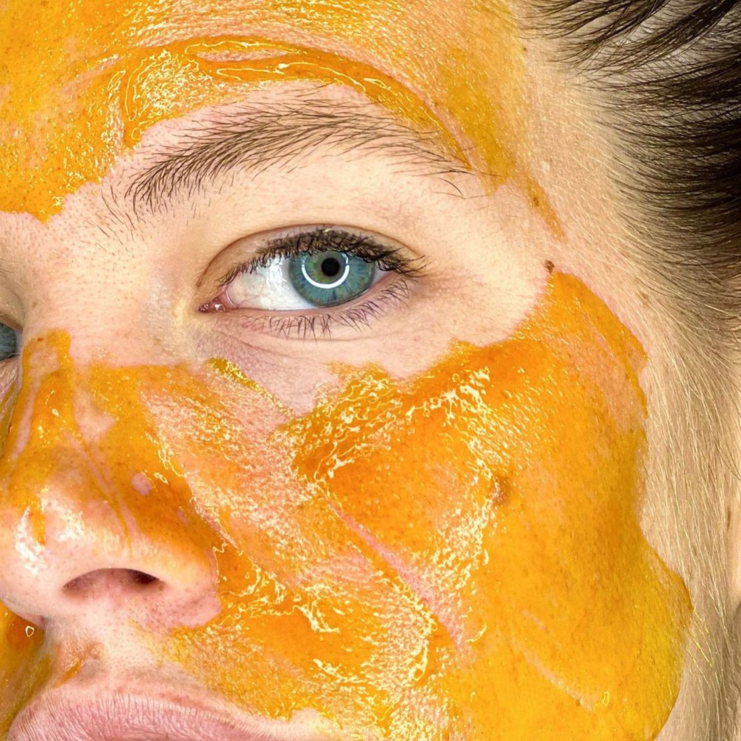 Woman applying LIA Cosmétiques Peeling Mask – vibrant orange gel-textured exfoliating mask