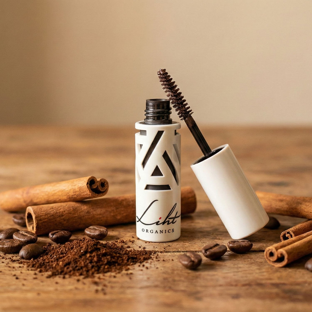 Open Liht Organics mascara bottle on a wooden table with coffee powder and coffee grains around.
