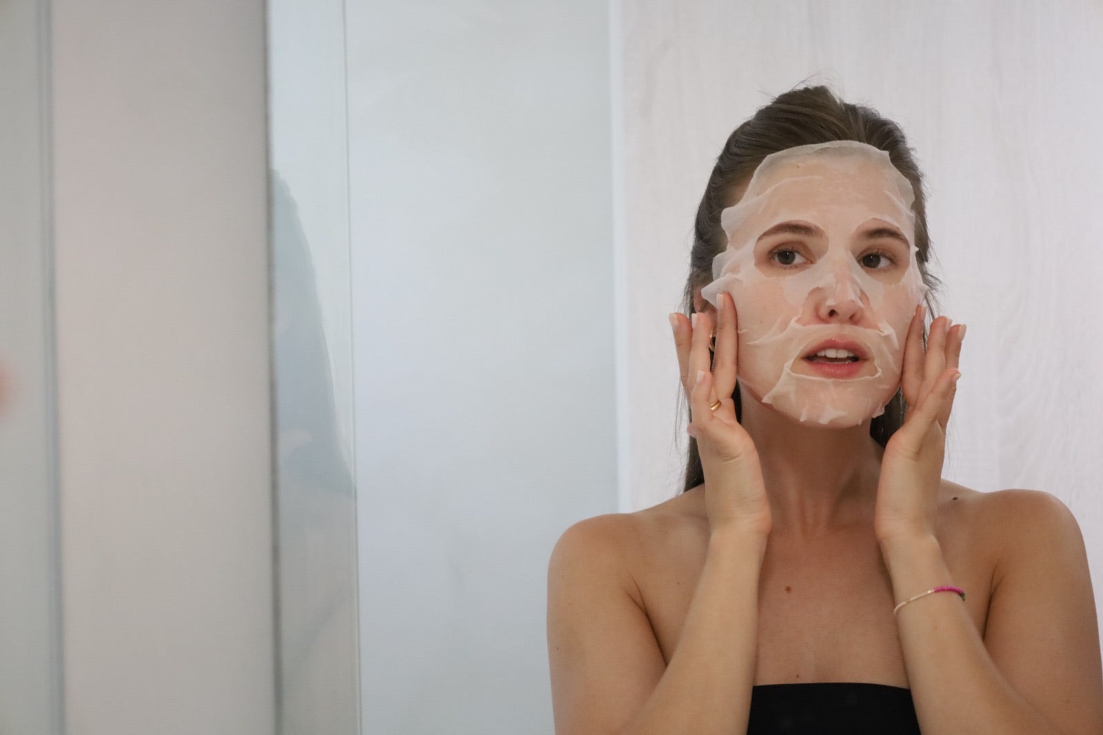 Woman applying sheet mask from Snow Fox Skincare — clean, high-performance skincare for sensitive and rosacea-prone skin.