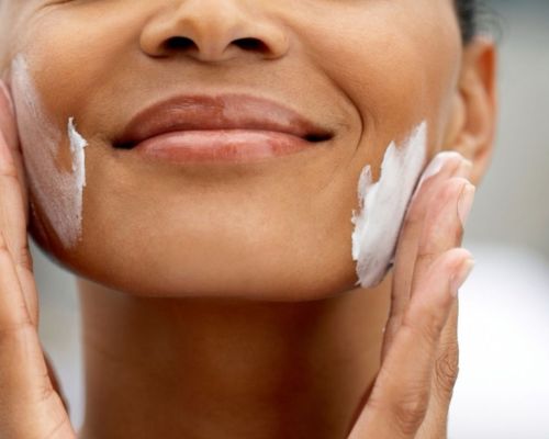 Close up of a woman's face applying moisturizer on her cheeks to fight dehydration